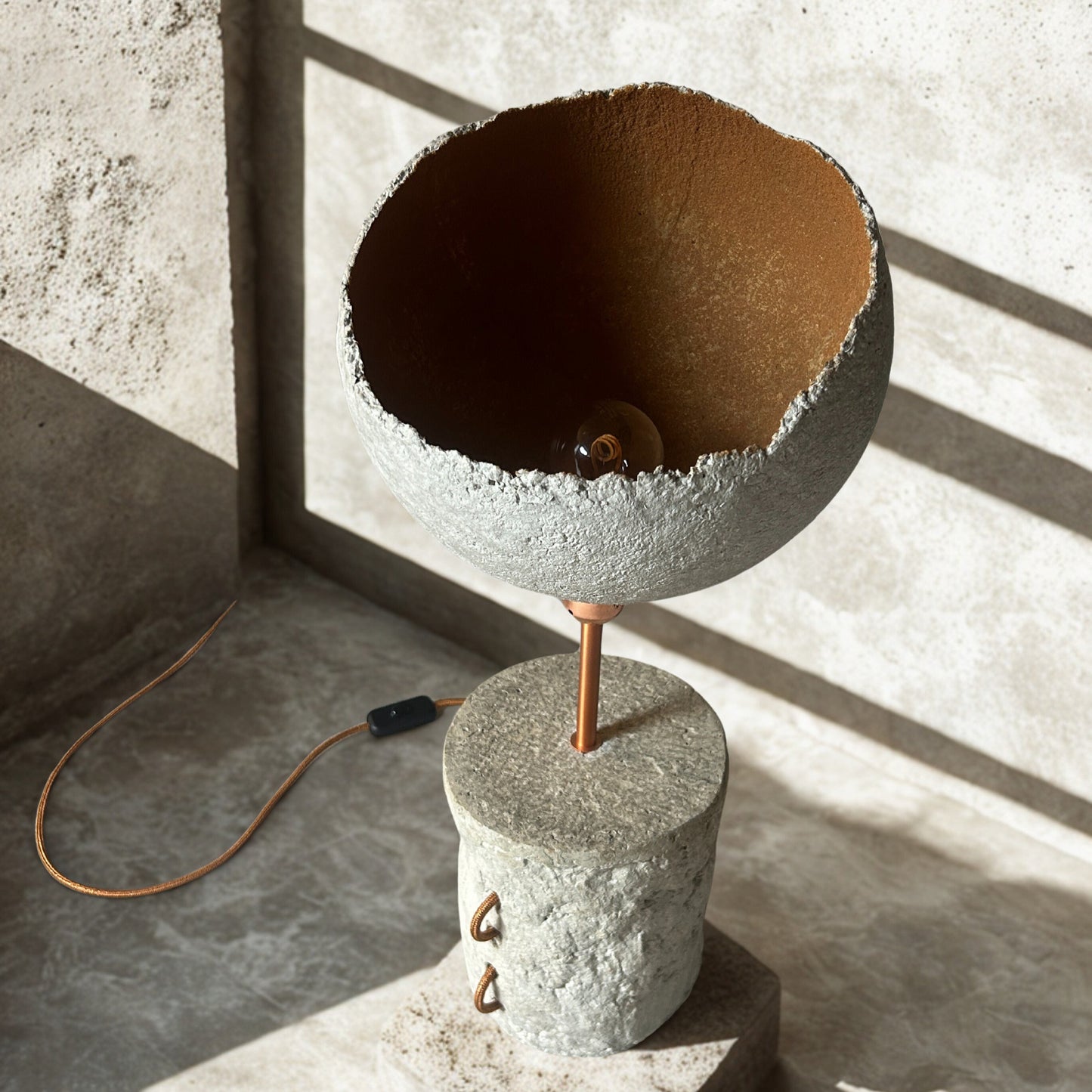 Concrete lamp with brown interior on a concrete floor