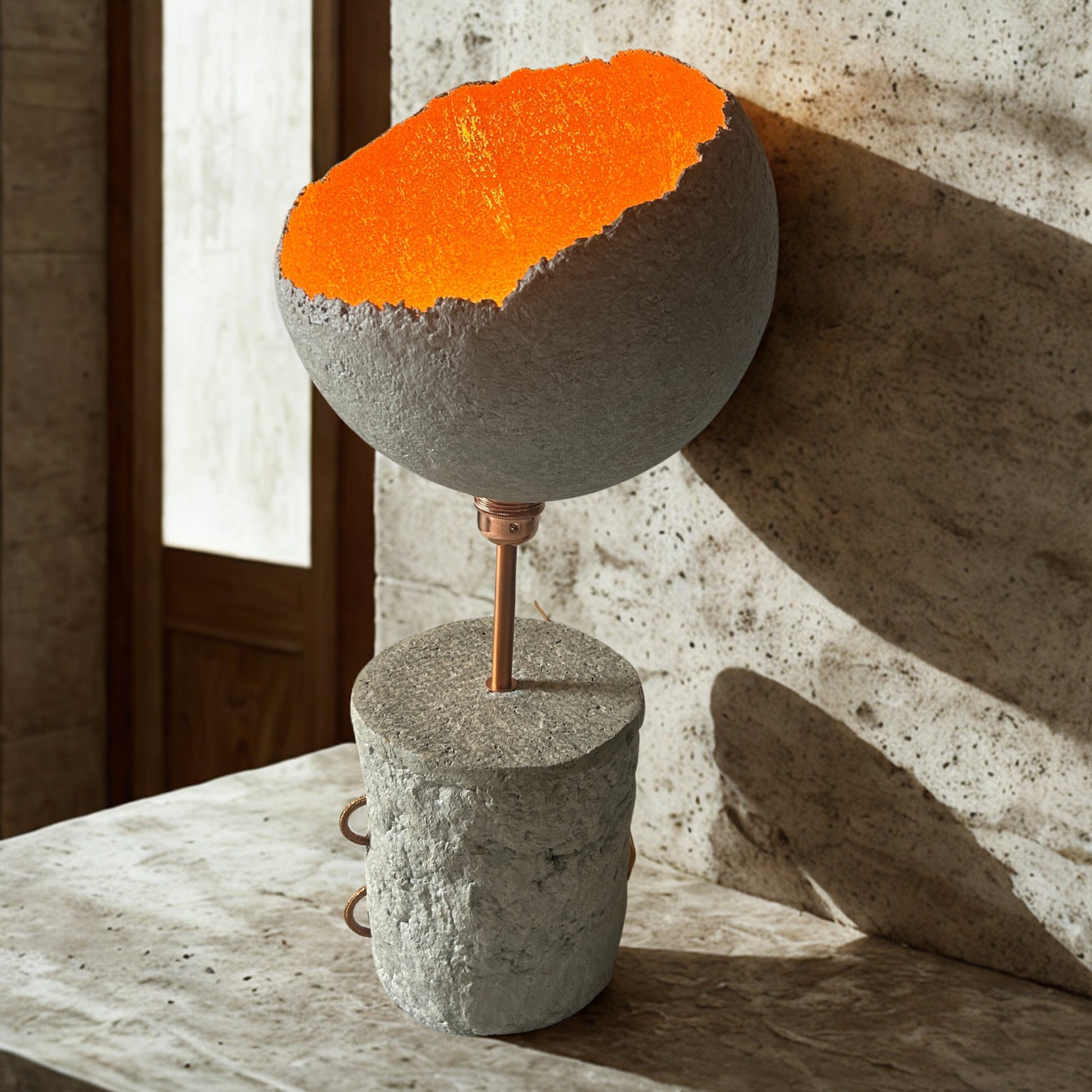 Cylindrical sculpture with orange top and gray base on a wooden surface.