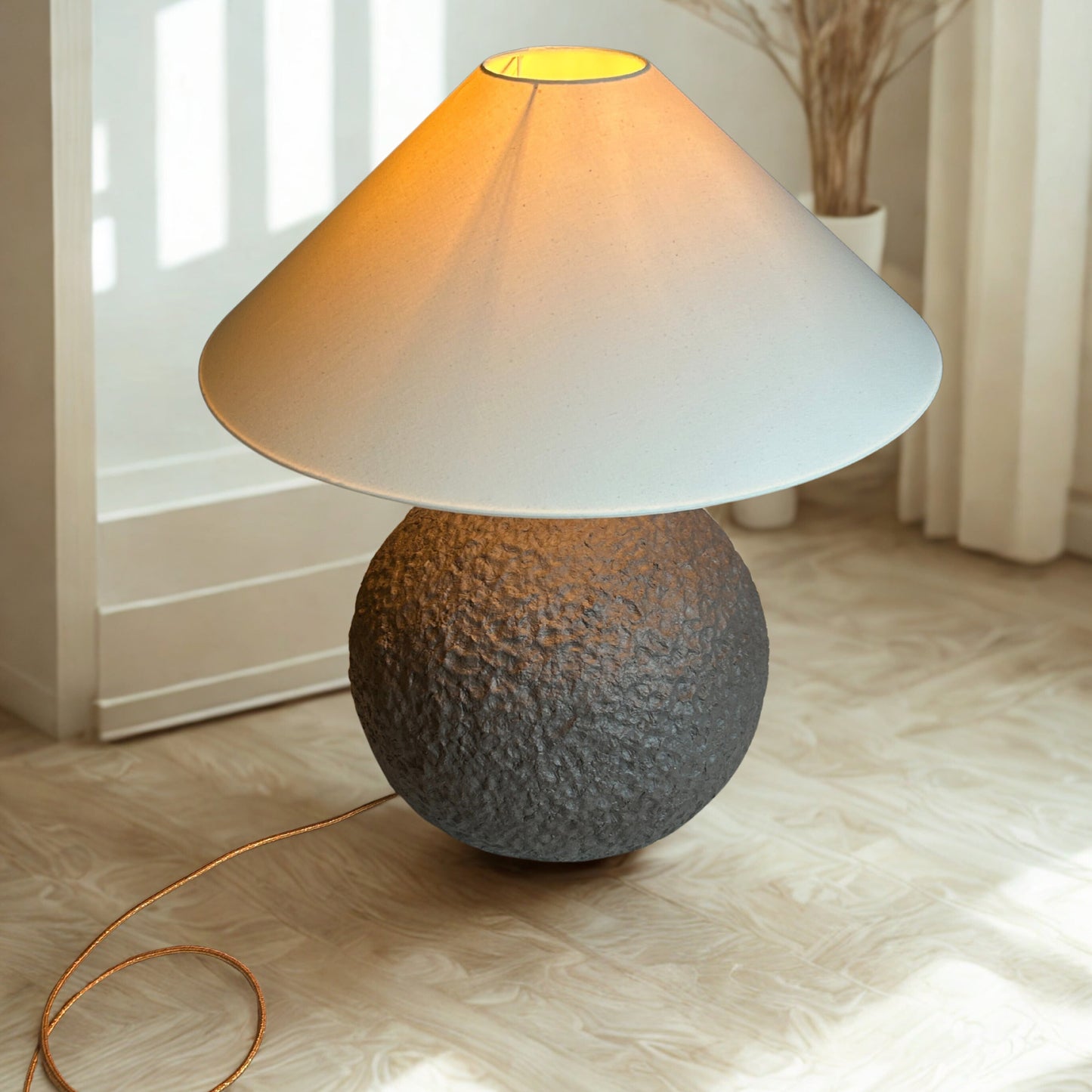 Table lamp with textured base and white shade on a light wooden floor.