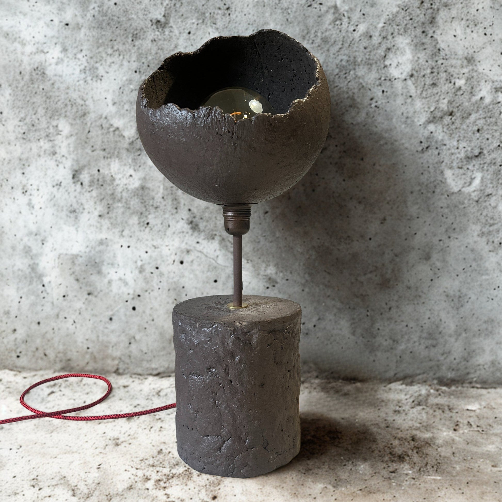 Vintage-style lamp with a concrete base against a textured wall.