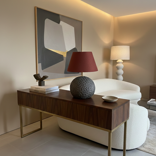 Modern interior with a wooden console table, white armchair, and abstract art on a wall.