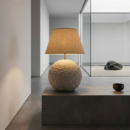 Decorative lamp with textured base and brown shade on a dark surface.